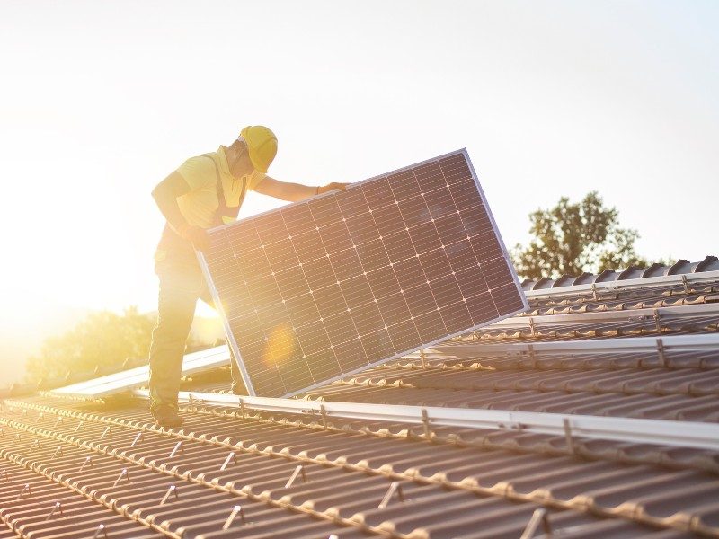 Arbeiter auf dem Dach mit Photovoltaik-Modul
